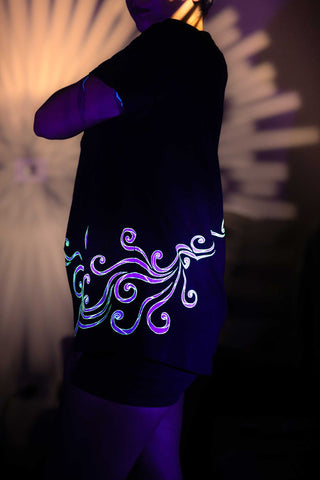 Person wearing a black shirt with glowing neon design in dark setting